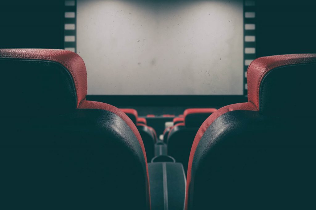 Une image captivante d'une salle de cinéma, avec des rangées de sièges confortables face à un grand écran.